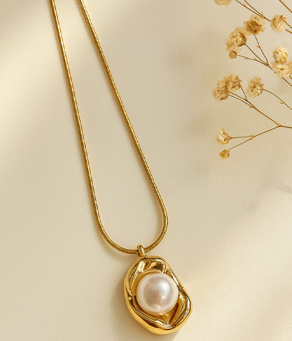 Gold pendant necklace with a white a pearl set in an irregular sculpted frame on a snake chain